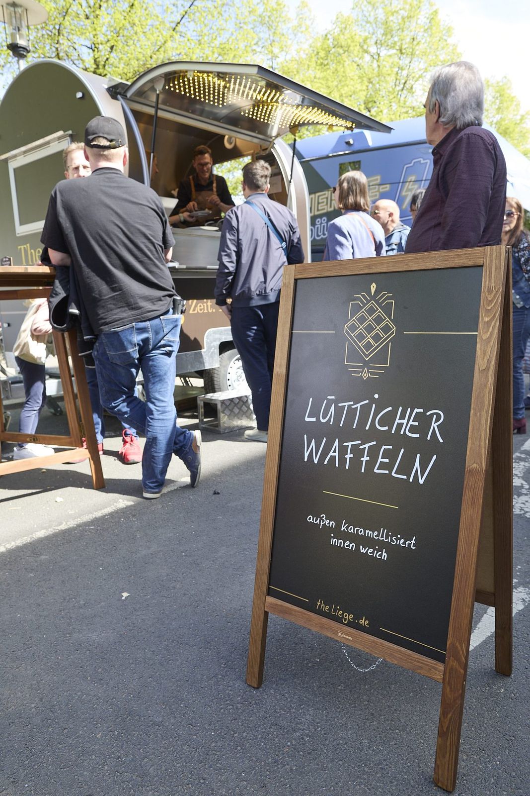Kreidetafel „Lütticher Waffeln – außen karamellisiert, innen weich“ vor dem Waffeltrailer